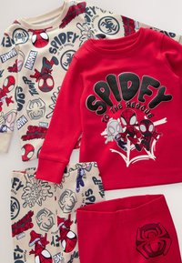 Pyjama pour enfants sur le thème de Spider-Man avec un haut rouge présentant trois personnages de Spider-Man et un pantalon beige orné de visages et de logos de Spider-Man.