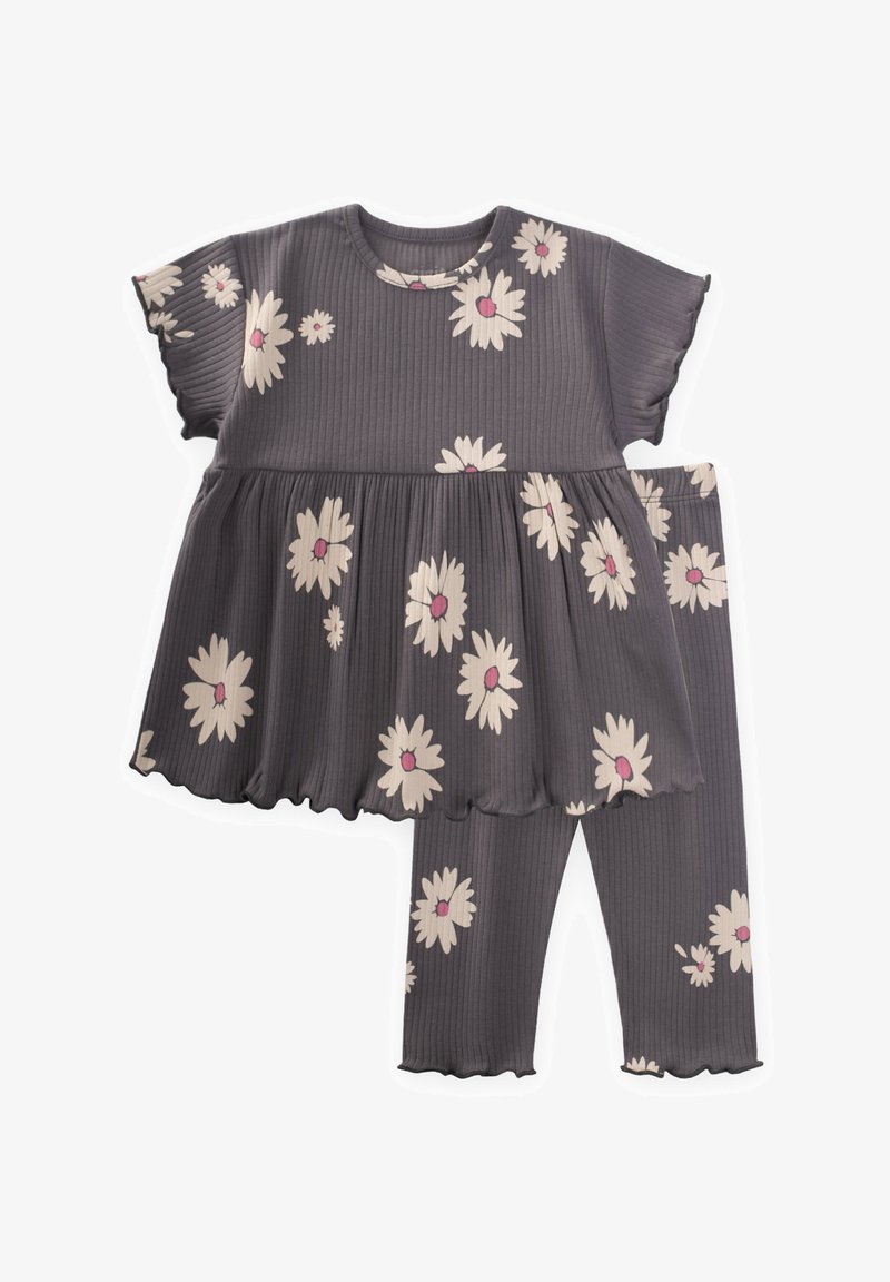 Sivobela oblačilo z rebrastim vzorcem, ki vključuje kratkosleeven top s širjenjem na robu in belimi marjeticami, v kombinaciji z ustreznimi leginami.