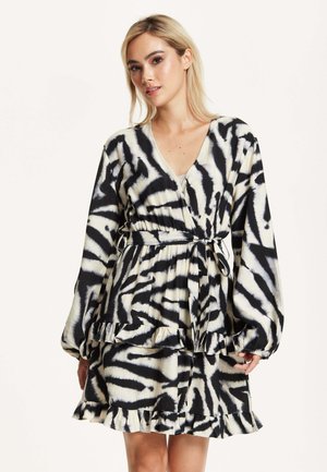 Black and white zebra-striped wrap dress with long balloon sleeves, ruffled hem, and a tie waist, made from soft, flowy fabric.