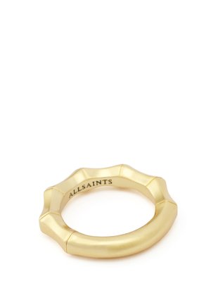 Bague de couleur or avec un design à bord festonné et "ALLSAINTS" gravé à l'intérieur de l'anneau sur un fond blanc.
