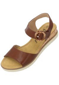 Brązowe skórzane sandały z szerokim paskiem z przodu, regulowanym paskiem wokół kostki, obcasem owiniętym korkiem oraz beżową gumową podeszwą. Płaska wkładka z detalami ściegów.