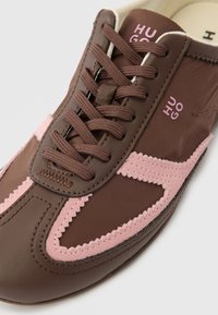 Καφέ και ροζ αθλητικό παπούτσι με κορδόνια, με υφή σουέτ στο τελείωμα και λογότυπο στην πλευρά και στη γλώσσα.