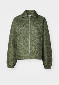 Pikowana oliwkowa kurtka z stojącym kołnierzem, zamkiem błyskawicznym z przodu, elastycznymi mankietami oraz fakturą w kwiatowy wzór. Posiada okrągły uchwyt zamka.