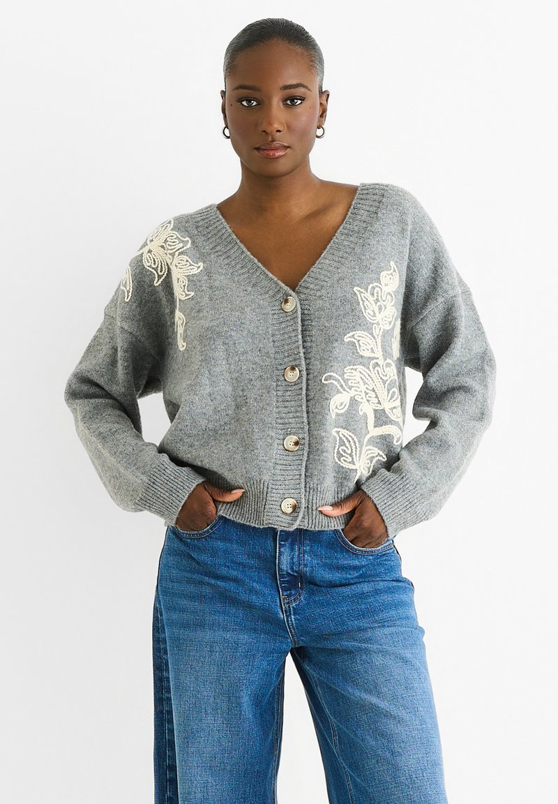 Gray knitted cardigan with embroidered floral design in cream, V-neckline, front button closure, wide sleeves, and ribbed cuffs.
