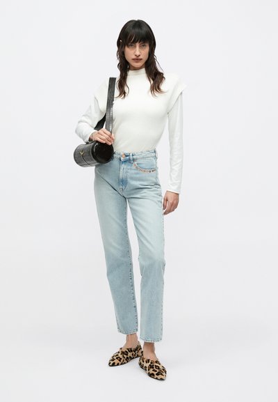 Λευκό πλεκτό πουλόβερ με λεπτομέρειες στους ώμους, ανοιχτό μπλε τζιν, φλατ παπούτσια με λεοπάρ μοτίβο και υφασμένη μαύρη στρογγυλή τσάντα χειρός.