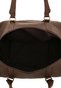 Brązowa skórzana torba z dwoma solidnymi uchwytami i zapięciem na zamek. Wnętrze jest w ciemnym materiale, przestronne, bez dodatkowych kieszeni czy przegród.