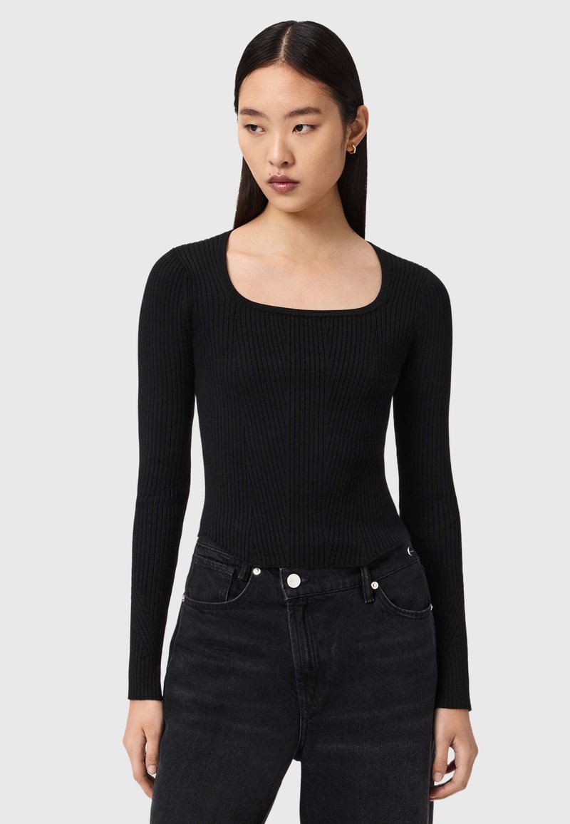 Czarny prążkowany top z długim rękawem i kwadratowym dekoltem, o dopasowanym kroju i fakturowanej tkaninie. W zestawie z ciemnymi jeansami z wysokim stanem.