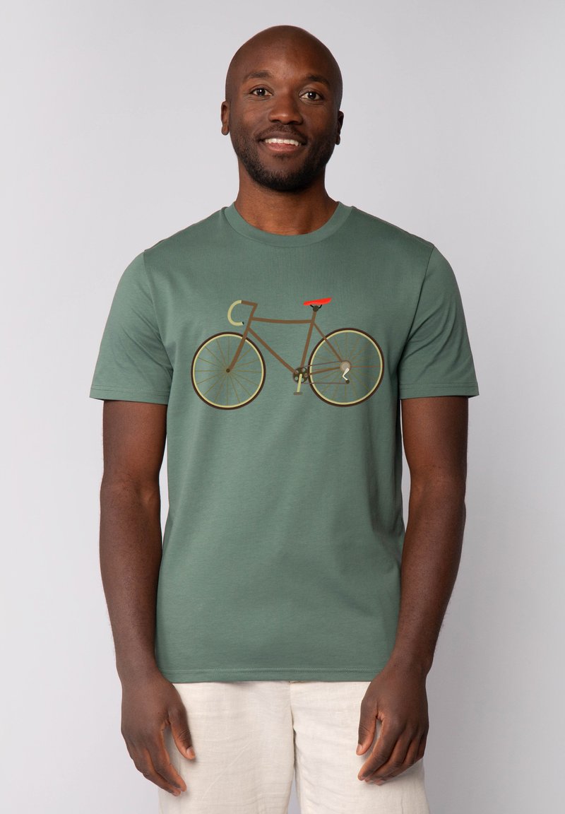 Groene katoenen t-shirt met een fietsafbeelding in bruin en een rode zitting. Korte mouwen en een ronde halsontwerp. Zachte textuur.