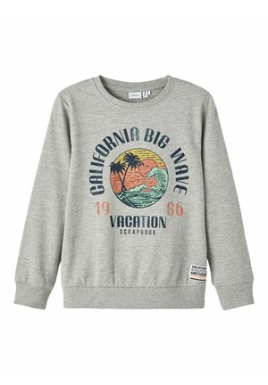 Sweat-shirt gris clair avec motif palmier et vague, texte "California Big Wave 1986 Vacation Scrapbook," et petite étiquette au bas de l'ourlet.