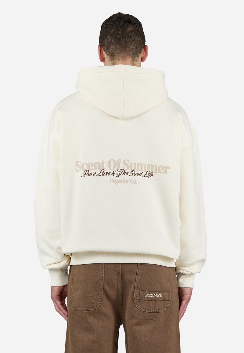 Sweat à capuche crème avec une grande capuche et des poignets côtelés. Présente "Scent of Summer" et le logo en marron clair dans le dos. Fabriqué en tissu doux.