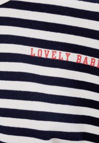 Tessuto a strisce navy e bianco con testo rosso "LOVELY BABY." Texture morbida, vestibilità regolare e strisce orizzontali creano un design classico.