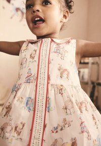 Vestito da bambina in tessuto rosa chiaro con stampa di animali da fattoria giocosa, piping rosso, colletto e dettagli con bottoni sulla parte anteriore.