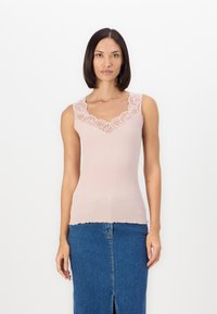 Light pink ribbed tank top with a lace-trimmed v-neckline, scalloped hem, paired with a blue denim skirt featuring a front slit.