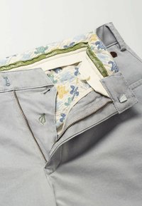 Gray fabric trousers featuring a green and patterned waistband interior, with a metal zipper and button closure.