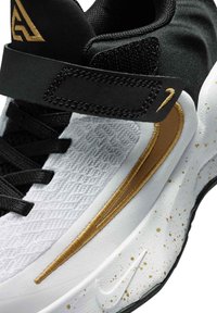 Zapatilla en blanco y negro con detalles en dorado. Fabricada con materiales textiles y sintéticos. Presenta un upper texturizado, cordones y una correa de Velcro.