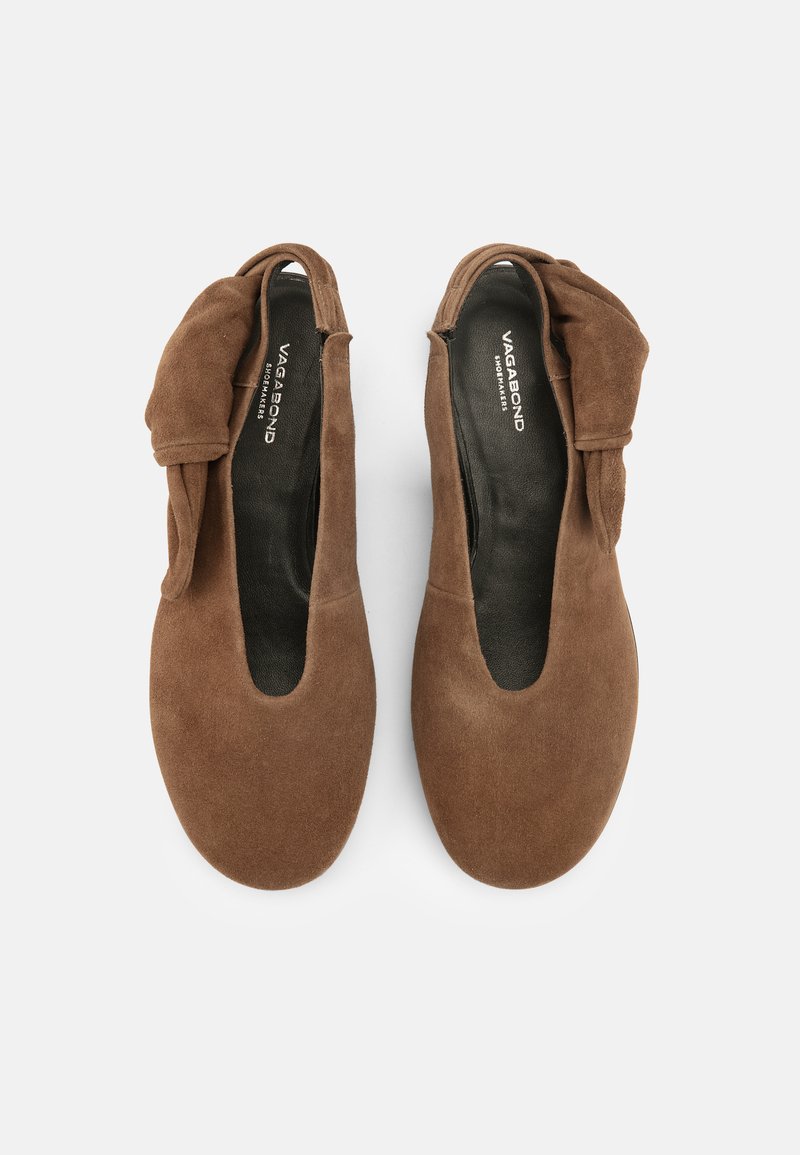 Paar braune Wildleder-Slipper mit weichem Knoten-Detail an den Seiten und schwarzen Innensohlen, innen mit „Vagabond Shoemakers“ gebrandet.