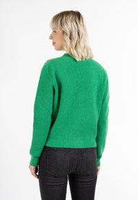 Suéter verde de punto a rayas con cuello redondo y mangas largas, con detalles decorativos en el hombro y un dobladillo ajustado.