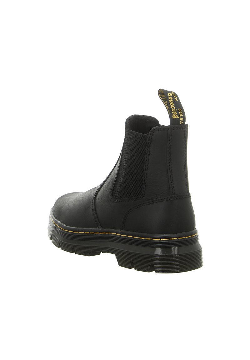 Black leather Chelsea boot with elastic side panels, raised heel, and yellow stitching detailing on the sole. Features a pull tab for easy wear.