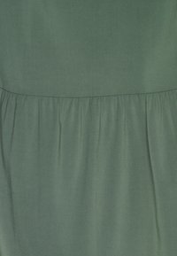 Vestido de tecido verde com uma textura suave, detalhe na cintura franzida e um design simples, sem padrões nem acabamentos em metal.