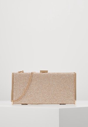 Pochette rectangulaire dorée pailletée avec une bandoulière chaîne dorée et une fermeture à fermoir, présentée sur une surface blanche.