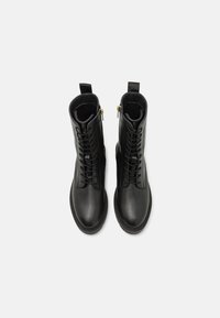 Black leather ankle boots with a smooth finish, featuring a lace-up front, side zippers, and pull tabs. Textured soles with stitching accents.