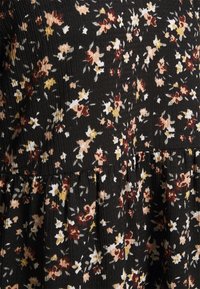 Svart blommig klänning i ett texturerat tyg med små blommor i nyanser av rött, rosa, gult och vitt; mockadesign som accentuerar.
