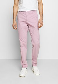 Rosa bomulds-chinos med slim fit, der har en knaplukning, frontlommer og bæres med hvide sneakers. Tekstureret og let materiale.