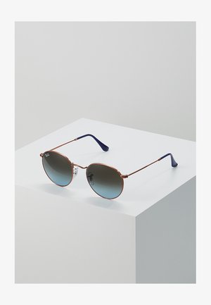 Solbriller med runde gradientlinser og tynn rosagull metallramme. Blå plast tempeltips. Plassert på en hvit utstillingspode.