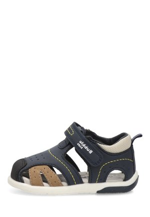 Sandalia infantil azul marino y beige con puntera abierta, cierre de velcro y talón acolchado, diseñada para comodidad y soporte.