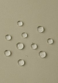 Przezroczyste krople wody na teksturowanej beżowej powierzchni, podkreślające sześciokątny wzór pod spodem. Obecne różne rozmiary i kształty kropli.