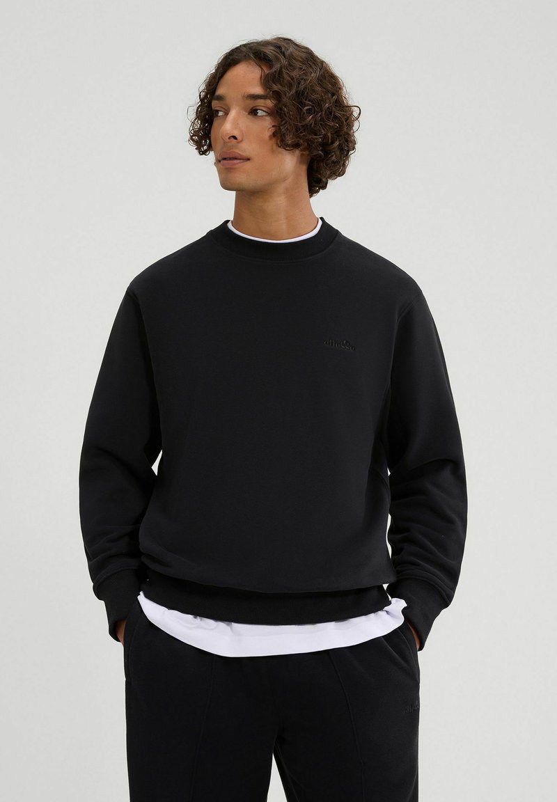 Schwarz sweatshirt mit Rundhalsausschnitt und gerippten Bündchen, versehen mit einem eingeprägten Logo auf der Brust und getragen über einem weißen T-Shirt.