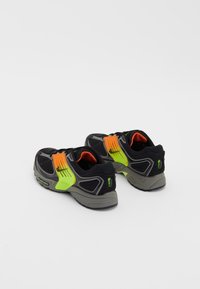 Černé a šedé sportovní boty s neonově zelenými a oranžovými akcenty, síťovinovým svrškem, polstrovanou podrážkou a výrazným designem.