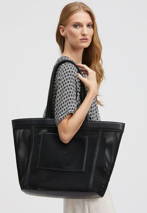 Schwarze Baumwolltasche mit Netzdesign und Lederbesatz. Verfügt über zwei stabile Griffe und ein eingeprägtes Patch auf der Vorderseite. Texturiertes Material.