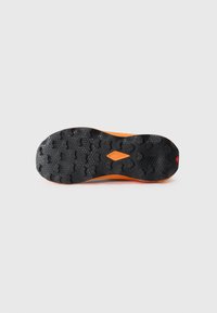 Semelle de chaussure en caoutchouc noir avec des motifs de traction multidirectionnels ; accent de semelle intercalaire orange le long du bord.