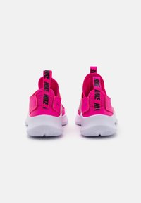 Une paire de baskets Nike rose vif vue de l'arrière avec des semelles blanches et des tirants de logo noirs sur fond blanc.