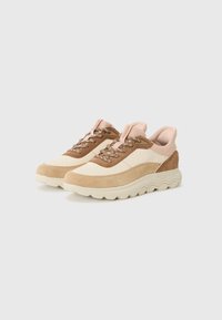 Scarpe da ginnastica beige e marrone chiaro con tomaia in suede texturizzato, suola in gomma e design con lacci, caratterizzate da dettagli rosa e colletto imbottito.