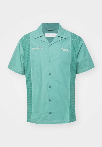 Turquoise színű, rövidujjú ing, gombos elülső résszel, texturált oldallapokkal és hímzett felirattal. Simaszerkezetű anyag, standard gallér kialakítással.