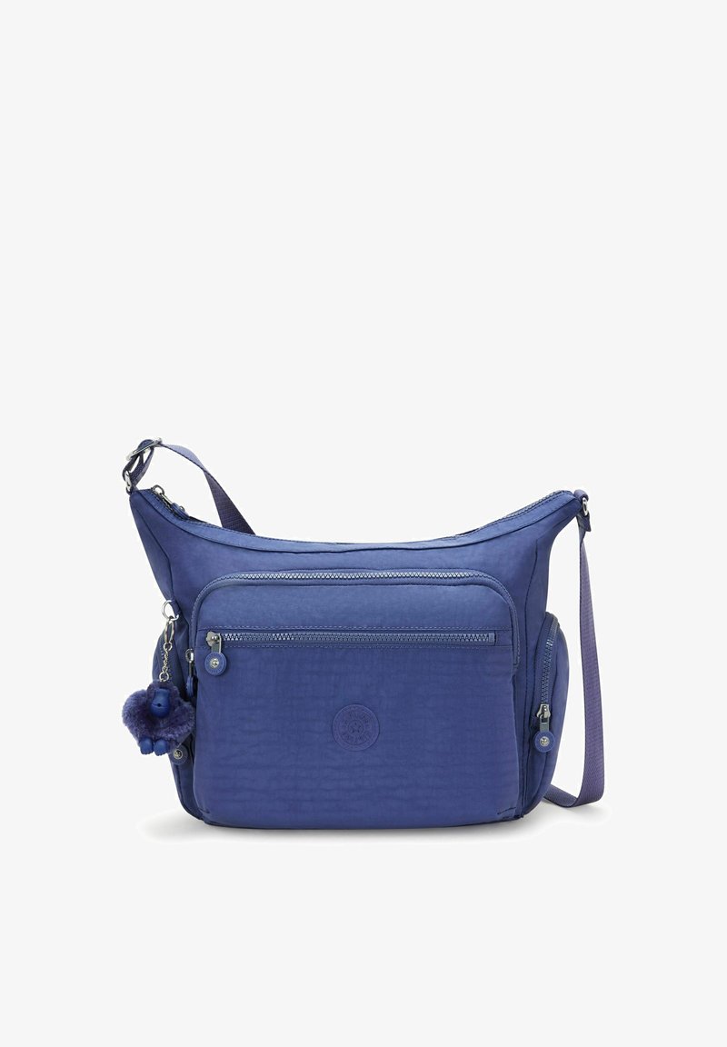 Blå axelväska i tyg. Har en zip-försedd framficka, justerbar rem och en fluffig nyckelringsaccessoar. Strukturerad yta.