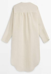 Longue robe beige en lin avec manches longues et détail froncé dans le dos, présentée à plat sur fond blanc.
