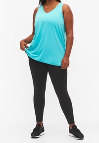 Lichtblauw mouwloos sporttop met een V-hals ontwerp, gecombineerd met zwarte legging en sportschoenen, met een gladde stofstructuur.