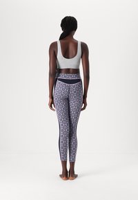 Grå sport-bh och mönstrade leggings med rosa och marinblå accenter, med geometriska mönster och hög midja.