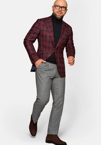 Bordowy i czarny kraciasty żakiet na czarnym golfie, w zestawieniu z szarymi spodniami i brązowymi botkami za kostkę. Gładka faktura i dopasowany krój.