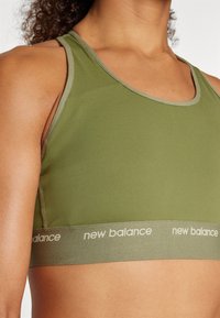 Olivovo zelená športová podprsenka s priliehavým dizajnom, s kontrastným svetlozeleným výstrihom a širokým pásom s logom "new balance".