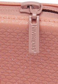 Ružičasta Havaianas torbica sa teksturom, zatvaračem i sjajnim detaljima, ovalnim uzorkom i branded zatvaračem. Izdržljiv materijal i kompaktni dizajn.