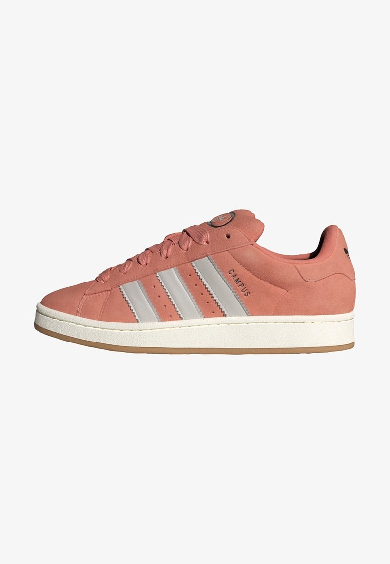 Pink suede sneaker featuring three silver stripes, a gum sole, and a round logo patch on the tongue, with a padded collar for comfort.
