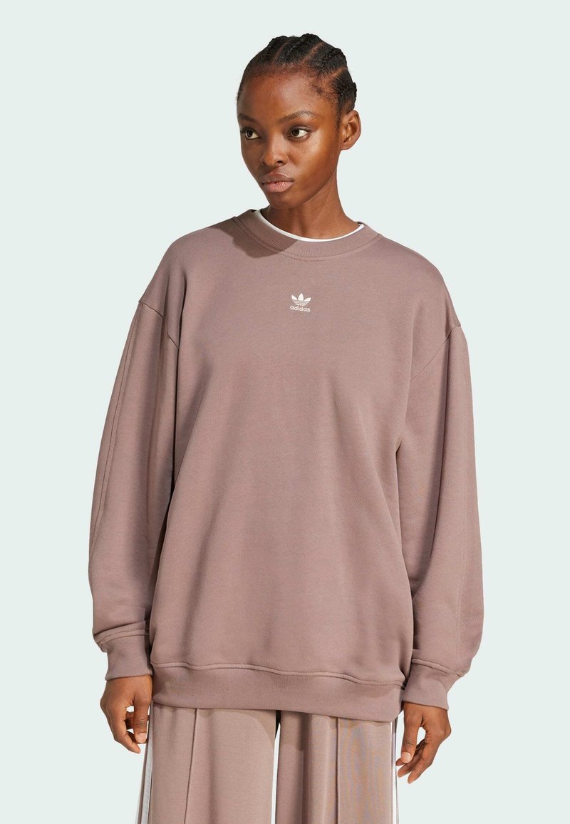 Felpa oversize color malva realizzata in morbido tessuto. Presenta un colletto e polsini a coste, con un piccolo logo bianco adidas sul petto.