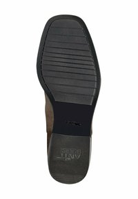Semelle de chaussure en caoutchouc noir avec rainures horizontales et logo. Le talon est arrondi, et la partie supérieure est en matériau semblable au daim de couleur fauve.