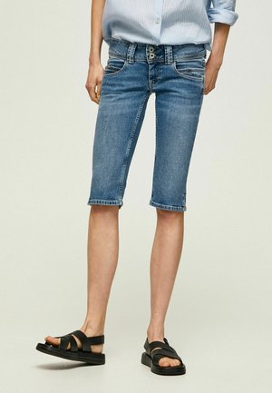 Lette denim Bermuda-shorts i lyseblå, med en tætsiddende silhuet, opsmøgte kanter, fem lommer og subtile syningsdetaljer. Parret med sorte sandaler.