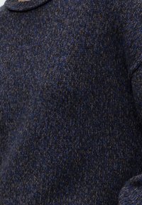 Gros plan sur un tissu en laine tricotée texturé bleu foncé et gris avec un détail de col plié.