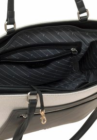 Grijze en zwarte handtas met twee ritscompartimenten. Het interieur heeft een zwarte voering met diagonale strepen en één kleiner zakje. Nepleer accenten.